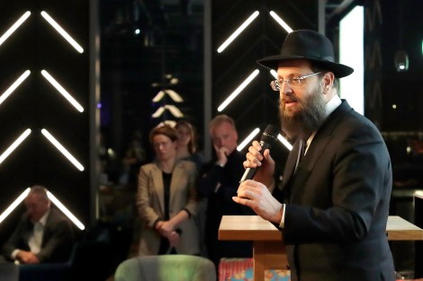 Rabbiner Teichtal spricht in ein Mikrofon. Im Hintergund stehen Leute und hören ihm zu.