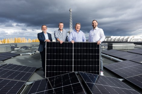 Frank Bro und Team halten auf dem Dach der Messe Berlin ein Solarpanel.
